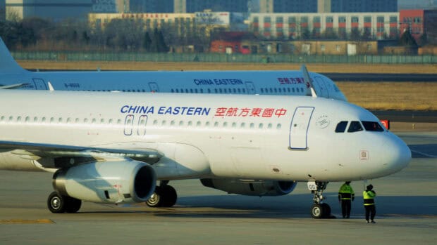 A China Eastern Airlines airplane is taxiing on the runway with airport staff nearby, HD Desktop Wallpaper