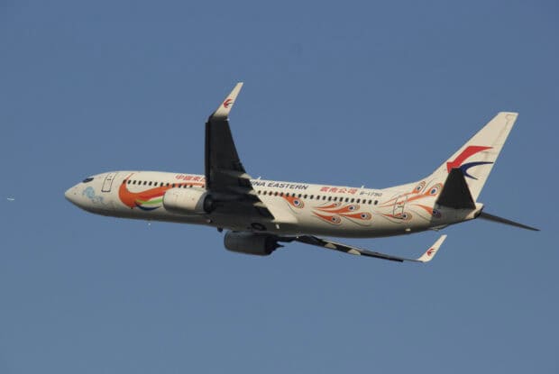 A China Eastern Airlines plane with colorful designs flies against a clear blue sky, HD Desktop Wallpaper