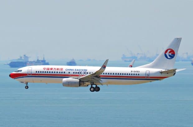 A China Eastern Airlines jet is captured in flight above calm ocean waters, 2K Desktop Wallpaper