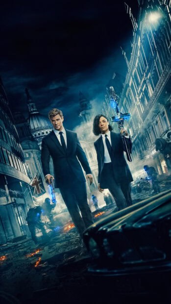 Chris Hemsworth stands with a partner in a ruined city holding futuristic weapons, HD Mobile Wallpaper