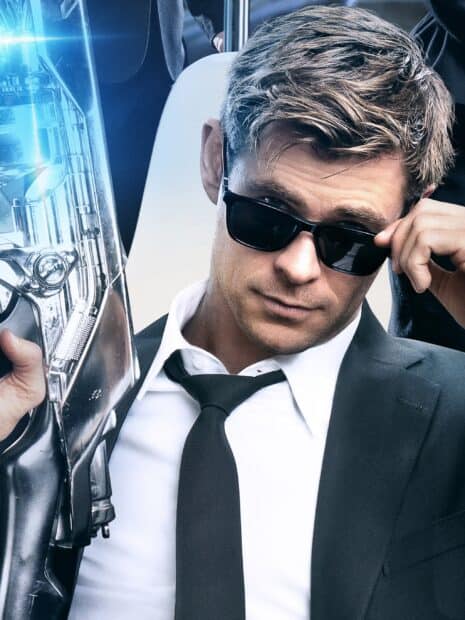 Chris Hemsworth in a black suit and sunglasses holding a futuristic weapon in a Men In Black setting, 2K Desktop Wallpaper