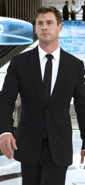 Chris Hemsworth wearing a black suit and tie in a scene from Men In Black, 2K Mobile Wallpaper