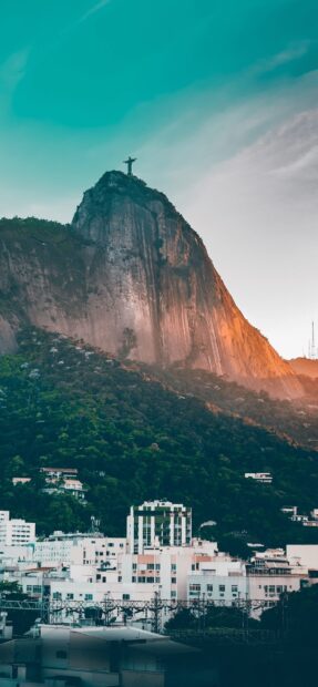 The Christ the Redeemer statue overlooks the green hills and buildings in Rio de Janeiro, 2K Phone Wallpaper