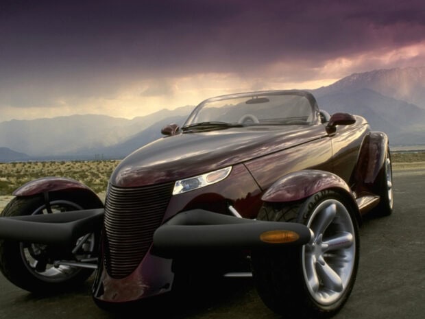 A Plymouth Prowler is parked on a highway with mountains under a dramatic sky, HD Desktop Wallpaper