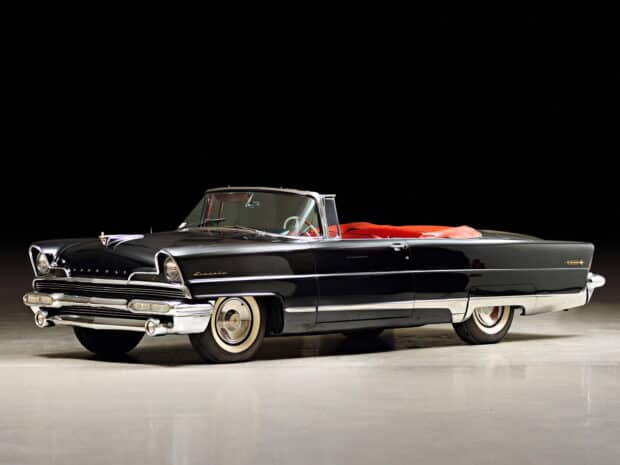 A classic black Lincoln convertible car is displayed in a studio setting with a red interior and a sleek design, HD Desktop Wallpaper
