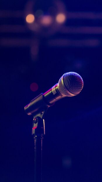 A classic microphone stands on a stand under colorful stage lights in a dark environment, HD Mobile Wallpaper