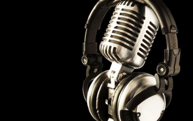 A classic microphone is hanging with headphones against a black background featuring microphone wallpapers, 2K Desktop Wallpaper