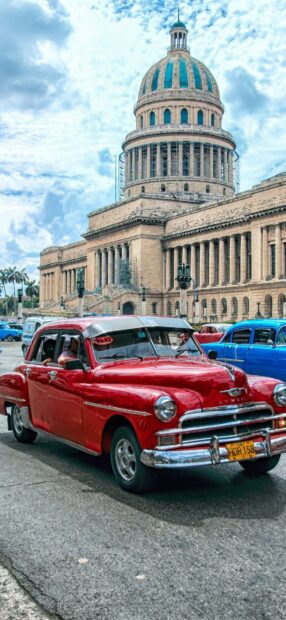 A classic red car drives past historic Havana Cuba under a bright sky, HD Mobile Wallpaper