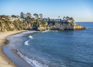 People enjoying the water at Laguna Beach with cliffs and houses nearby, 2K Desktop Wallpaper