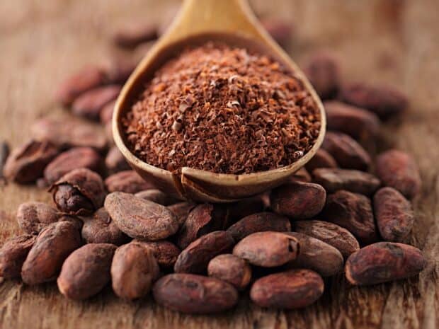 A wooden spoon filled with cocoa powder surrounded by cocoa beans on a wooden surface with Cocao Wallpapers, HD Desktop Wallpaper