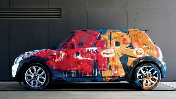 A Mini Cooper covered in vibrant abstract paint art is parked indoors, HD Desktop Wallpaper