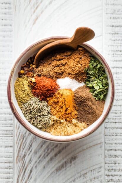 A bowl contains a colorful assortment of seasoning spices with a wooden spoon inside, HD Mobile Wallpaper