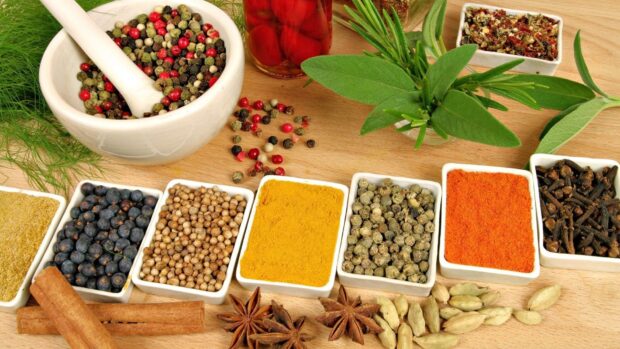 A colorful assortment of seasoning spices arranged in white bowls and fresh herbs on wood, HD Desktop Wallpaper