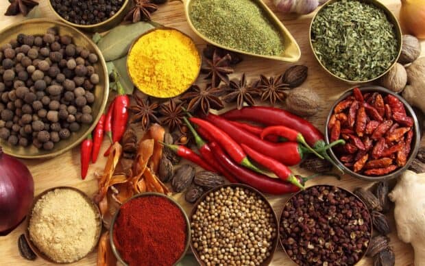 A vibrant assortment of seasoning spices arranged on a wooden surface, HD Desktop Wallpaper