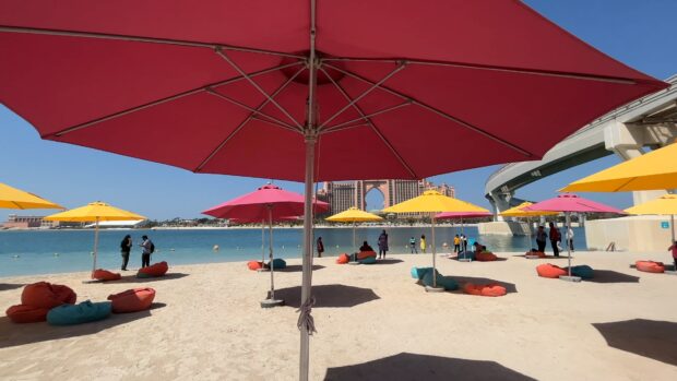 People enjoying the sunny beach under colorful beach umbrellas near the water, 4K Desktop Wallpaper