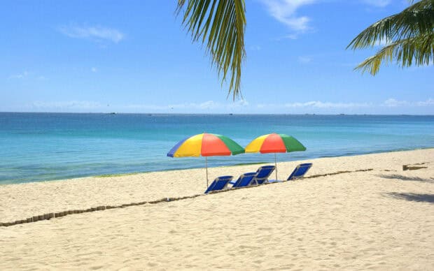 Two colorful beach umbrellas shade blue chairs by the ocean, HD Desktop Wallpaper