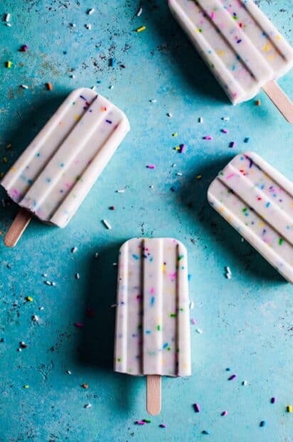 A close up of colorful cream popsicle with sprinkles scattered on a blue surface, 2K Phone Wallpaper