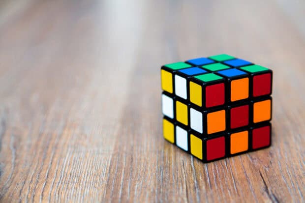 A colorful cube puzzle resting on a wooden table with a blurred background, HD Desktop Wallpaper