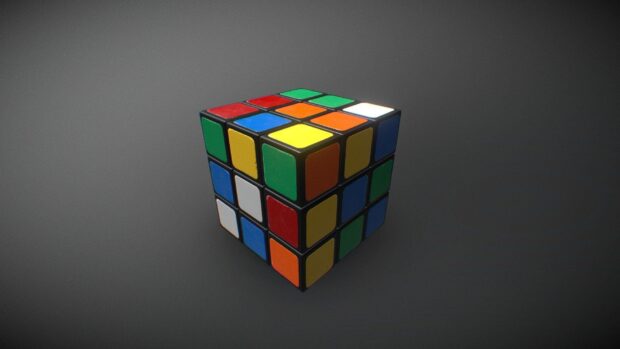 A colorful cube puzzle with mixed stickers resting on a plain surface, HD Desktop Wallpaper