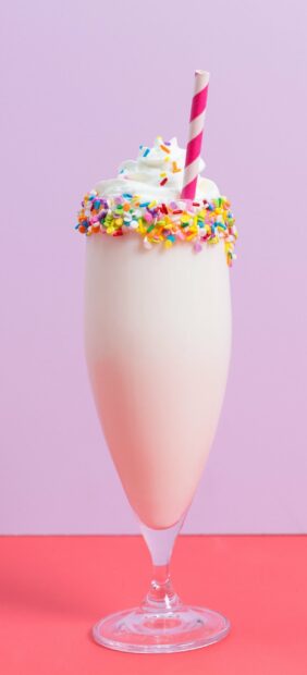 A milkshake with whipped cream and colorful sprinkles in a tall glass, 2K Mobile Wallpaper