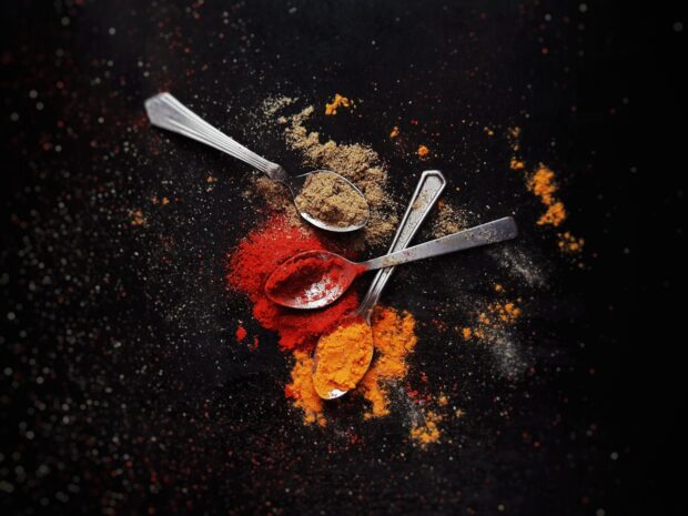 Various seasoning powders on spoons scattered on a dark surface creating a vivid contrast in seasoning wallpapers, 2K Desktop Wallpaper