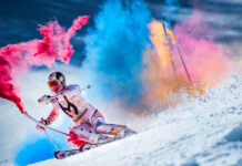 A skiing athlete is performing with vibrant colored powder on snow, 2K Desktop Wallpaper