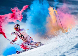 A skiing athlete is performing with vibrant colored powder on snow, 2K Desktop Wallpaper