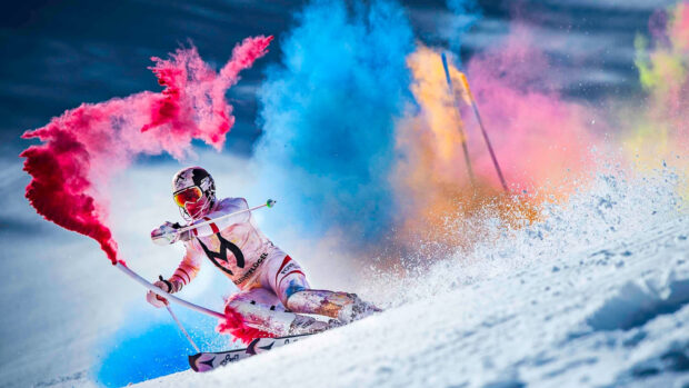 A skiing athlete is performing with vibrant colored powder on snow, 2K Desktop Wallpaper