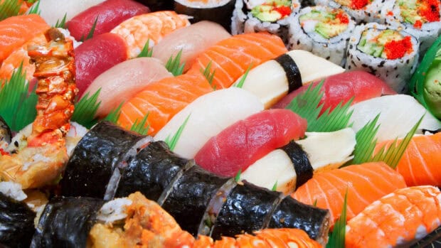 A variety of sushi rolls and nigiri are arranged in a colorful dish featuring fresh fish and rice, 4K Desktop Wallpaper