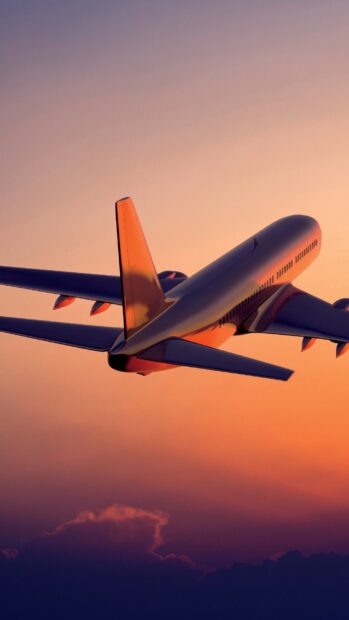 A commercial aircraft flies through the colorful sunset sky with clouds below, 2K Phone Wallpaper