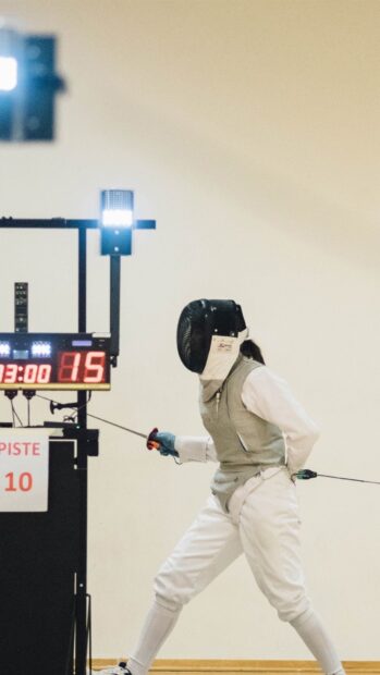 A skilled athlete competing in a fencing match wearing protective gear and holding a foil, HD Mobile Wallpaper