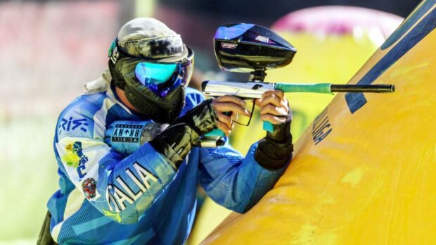 A paintball player wearing protective gear aims carefully during an outdoor game, HD Desktop Wallpaper