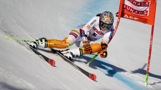 A skier in a racing suit turns tightly around a gate in a skiing competition, 2K Desktop Wallpaper
