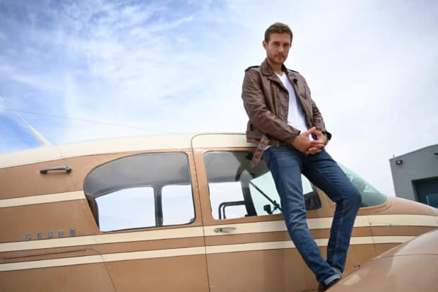 A confident man wearing a leather jacket stands next to a small private plane, The Bachelor Tv Series Wallpapers, 2K Desktop Wallpaper