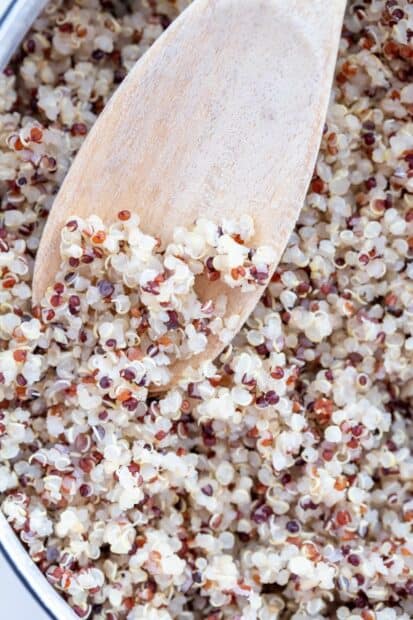A close up view of cooked quinoa grains with a wooden spoon in a bowl, 2K Mobile Wallpaper