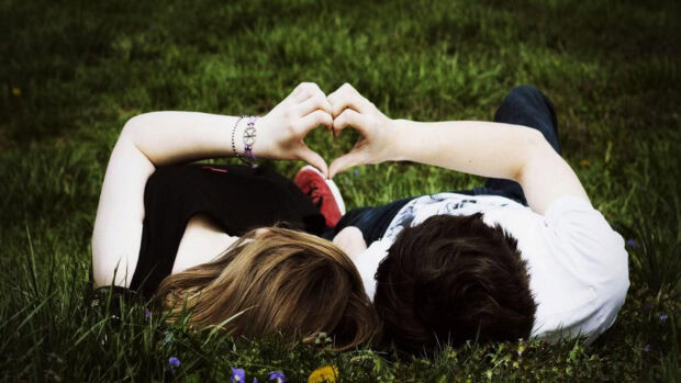 A couple lies on grass forming a heart shape with their hands symbolizing love and togetherness, HD Desktop Wallpaper