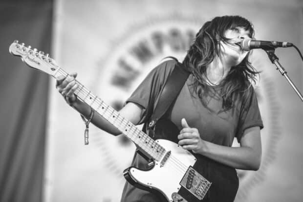 Courtney Barnett is playing guitar and singing into a microphone on stage, HD Desktop Wallpaper