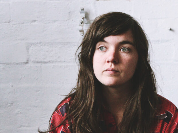 A thoughtful woman with long hair and green eyes in a red shirt represents Courtney Barnett wallpapers, HD Desktop Wallpaper