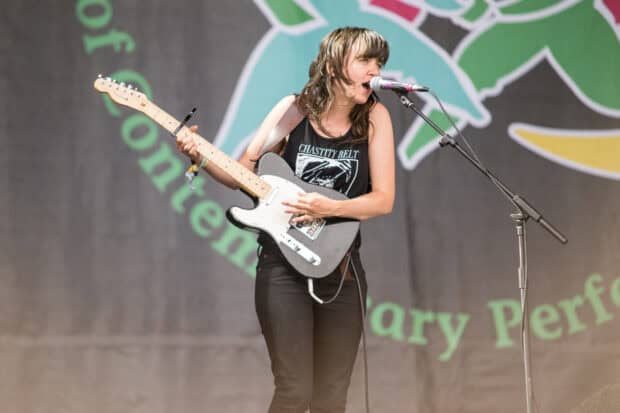 Courtney Barnett is playing guitar and singing into a microphone during a concert, HD Desktop Wallpaper