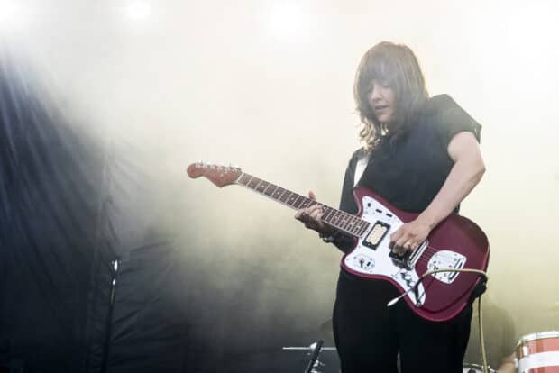 Courtney Barnett is performing live on stage with a red electric guitar in hand, HD Desktop Wallpaper