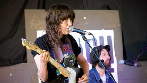 A female musician is singing into a microphone while playing an electric guitar, HD Desktop Wallpaper