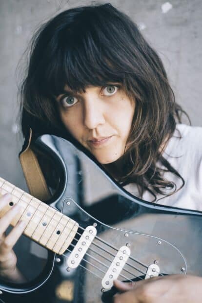 A close up of Courtney Barnett holding and playing an electric guitar with a focused expression, HD Mobile Wallpaper