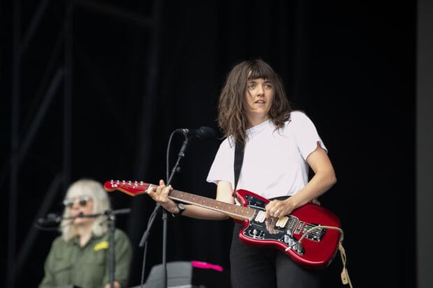 Courtney Barnett is performing live with a red electric guitar on stage, 2K Desktop Wallpaper