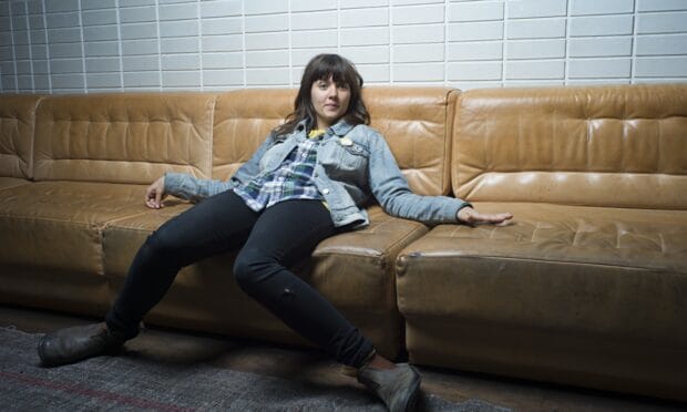 Courtney Barnett Wallpapers showing a relaxed pose on a brown leather couch, HD Desktop Wallpaper