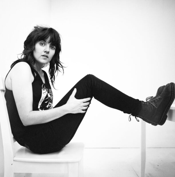 A woman wearing black clothes is sitting sideways on a white chair with her legs elevated, HD Desktop Wallpaper