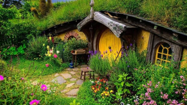 A charming cottage with a yellow door is surrounded by colorful flowers in the village, HD Desktop Wallpaper