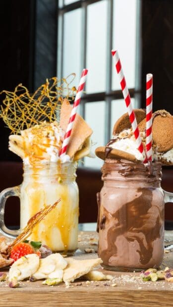 A creamy milkshake with caramel drizzle and banana slices topped with whipped cream, 2K Mobile Wallpaper