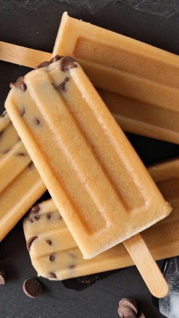 A close up of a creamy popsicle with chocolate chips on a dark surface for Popsicle Wallpapers, 2K Mobile Wallpaper