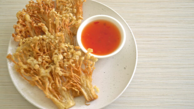 A plate of crispy enoki mushrooms served with a bowl of red dipping sauce on a wooden table, 4K Desktop Wallpaper