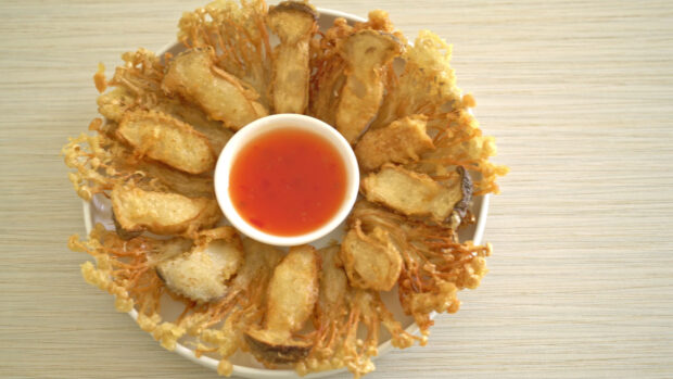 A plate of crispy fried enoki mushrooms served with a bowl of red dipping sauce on the table, 4K Desktop Wallpaper